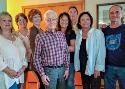 a group of past students stand with Eugene Snyder at the center.